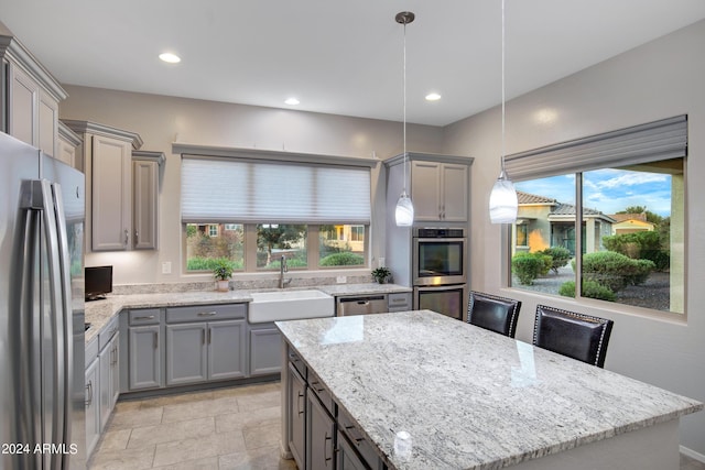 kitchen featuring decorative light fixtures, gray cabinets, a center island, sink, and stainless steel appliances