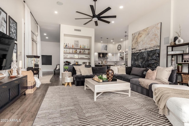 living room with dark hardwood / wood-style floors, ceiling fan, and bar area