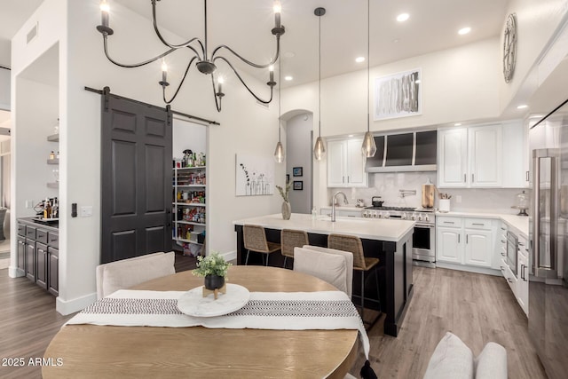 kitchen with pendant lighting, white cabinets, a high ceiling, high end appliances, and a barn door