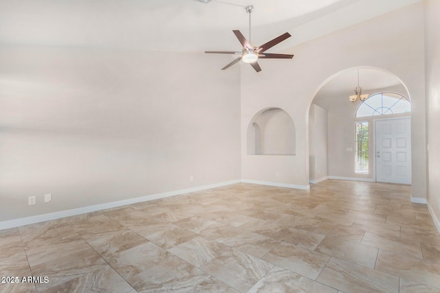 unfurnished room featuring high vaulted ceiling and ceiling fan with notable chandelier