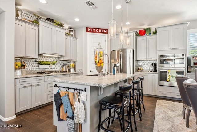 13088 N 91st Dr, Peoria, AZ 85381 - kitchen with appliances with stainless steel finishes, backsplash, dark wood-type flooring, recessed lighting, and a breakfast bar area