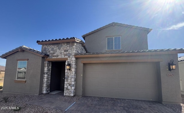 view of front facade with decorative driveway, a tile roof, stucco siding, a garage, and stone siding