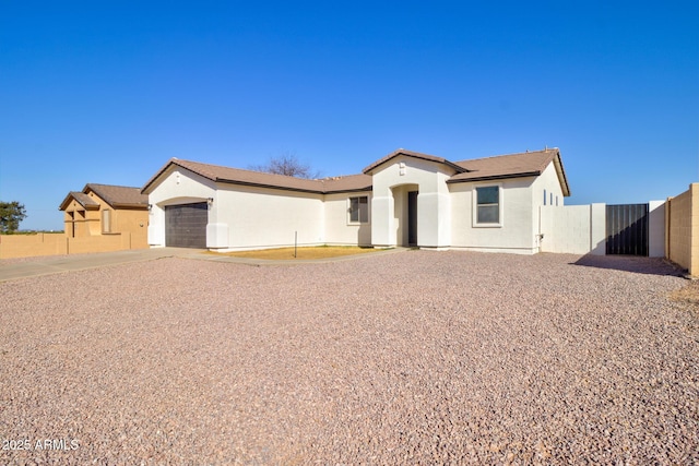 view of front of house with a garage, driveway, fence, and stucco siding