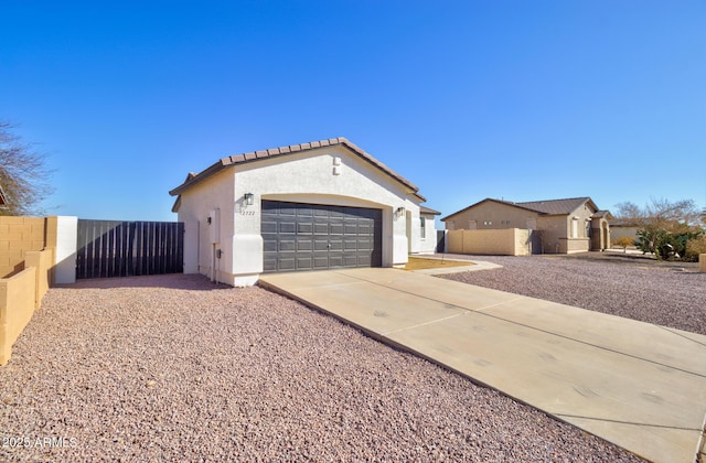 mediterranean / spanish home with stucco siding, fence, a garage, driveway, and a tiled roof