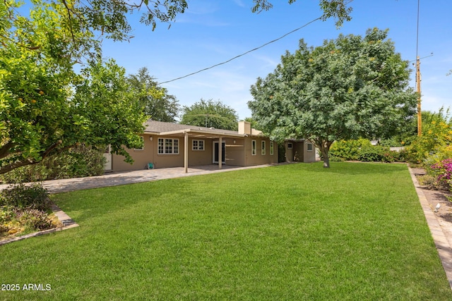 143 E Winter Dr, Phoenix, AZ 85020 - rear view of house featuring a patio area, a yard, stucco siding, and a chimney