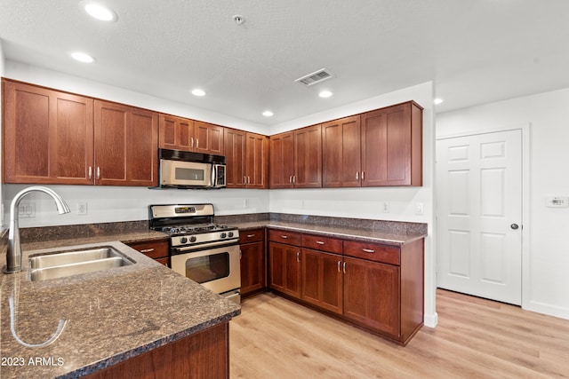 kitchen featuring a textured ceiling, appliances with stainless steel finishes, sink, and light hardwood / wood-style flooring