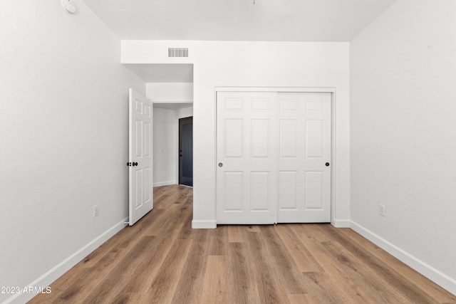 unfurnished bedroom with light hardwood / wood-style flooring and a closet