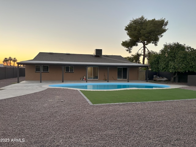 exterior space with central air condition unit, a patio, a yard, and a fenced in pool