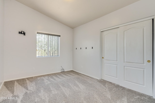 unfurnished bedroom with carpet flooring, a closet, and vaulted ceiling