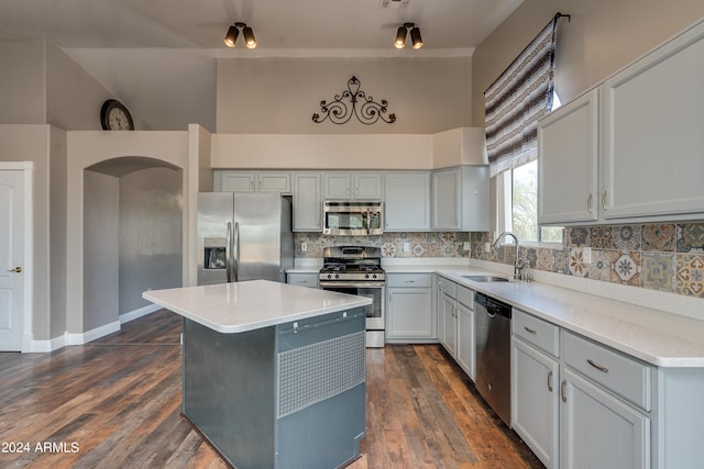 kitchen with dark wood-type flooring, a kitchen island, backsplash, stainless steel appliances, and sink