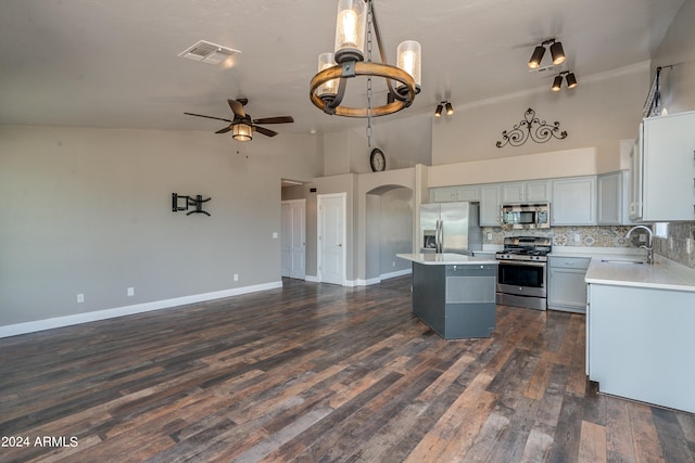 kitchen featuring dark hardwood / wood-style floors, ceiling fan, appliances with stainless steel finishes, backsplash, and a kitchen island