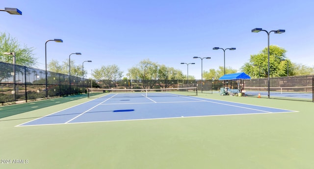 view of tennis court featuring community basketball court and fence