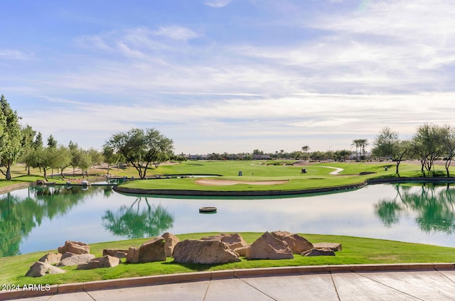 view of property's community with a water view, a yard, and golf course view