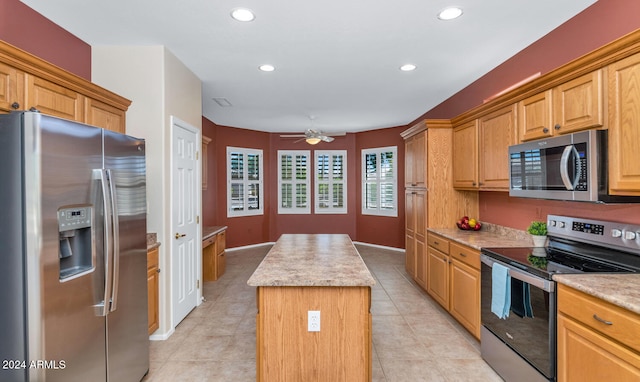 kitchen featuring a kitchen island, ceiling fan, stainless steel appliances, and light tile patterned floors