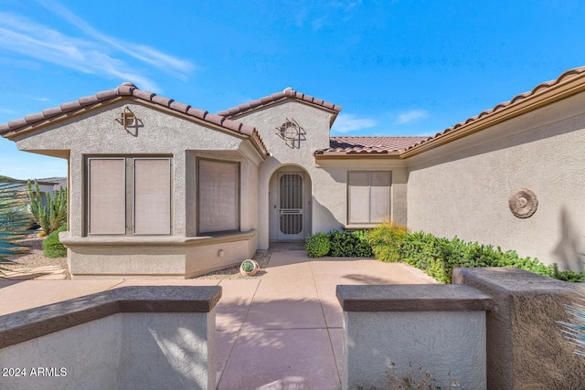 entrance to property with a patio area, a tiled roof, and stucco siding