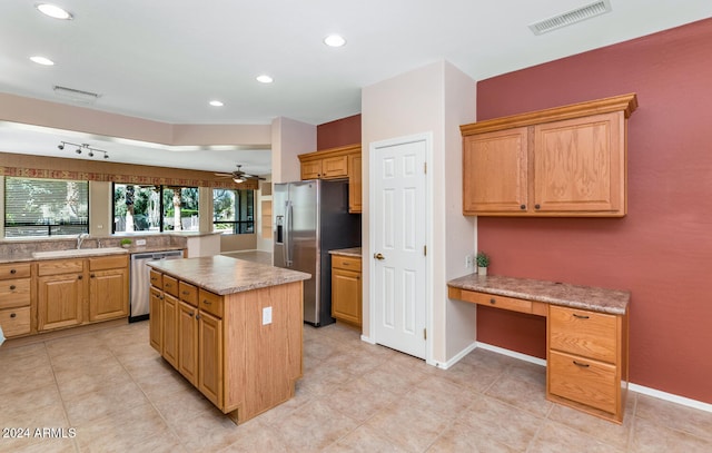 kitchen featuring a kitchen island, kitchen peninsula, stainless steel appliances, sink, and ceiling fan