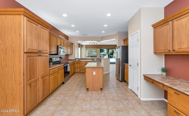 kitchen featuring recessed lighting, stainless steel appliances, a center island, built in study area, and light stone countertops