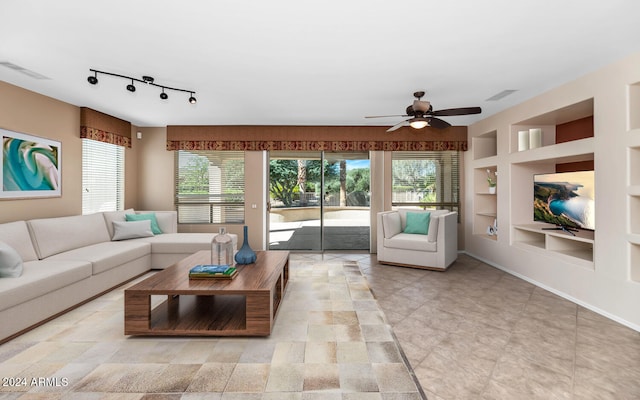 living area featuring built in features, visible vents, plenty of natural light, and a ceiling fan