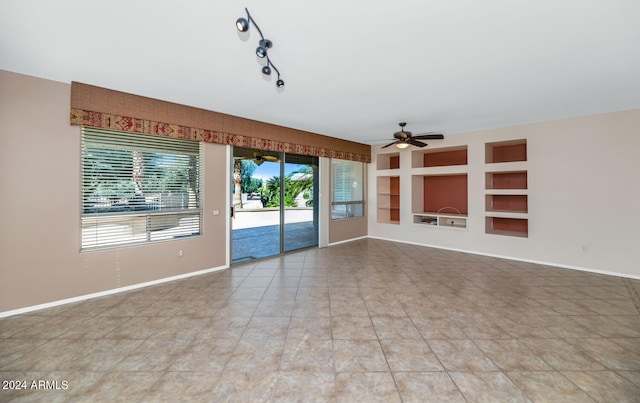 empty room with built in features, ceiling fan, baseboards, and light tile patterned floors