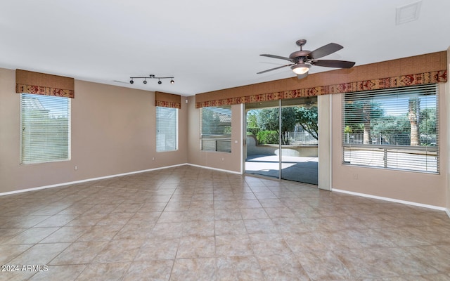 spare room with ceiling fan, light tile patterned floors, visible vents, and baseboards