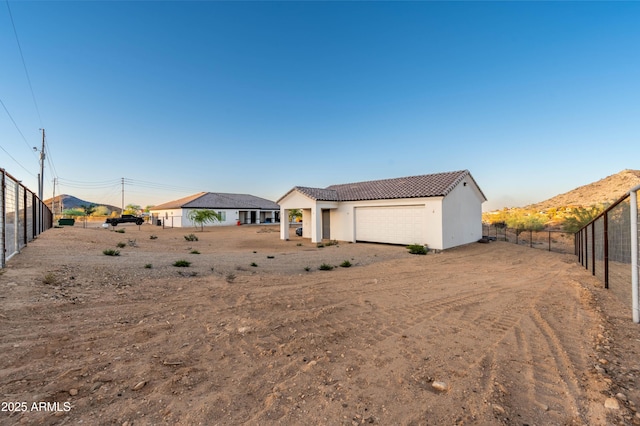 8017 S 143rd Ave, Goodyear, AZ 85338 - back of property featuring an attached garage, a tile roof, stucco siding, and dirt driveway