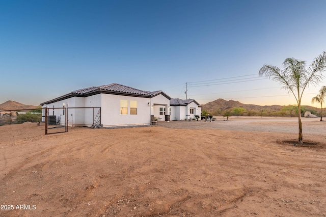 8017 S 143rd Ave, Goodyear, AZ 85338 - back of house at dusk with a tile roof, stucco siding, and a gate