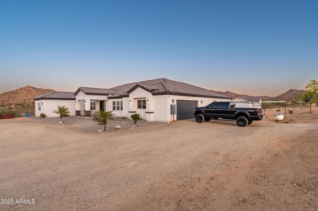 8017 S 143rd Ave, Goodyear, AZ 85338 - view of front of house featuring a garage, stucco siding, a tiled roof, and a mountain view