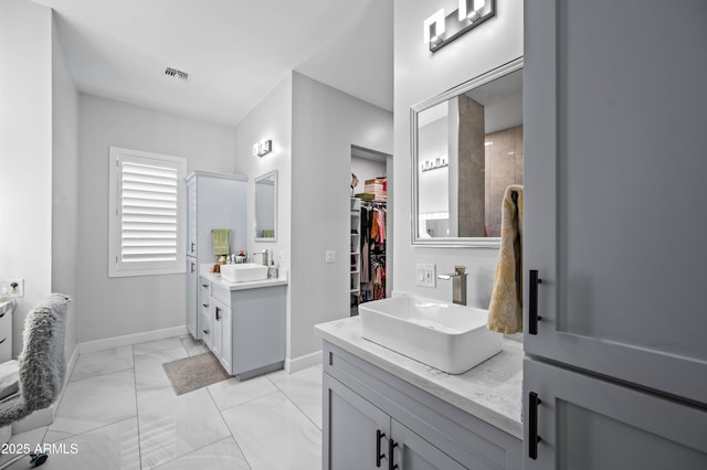 8017 S 143rd Ave, Goodyear, AZ 85338 - full bathroom featuring two vanities, a spacious closet, and marble look tiles