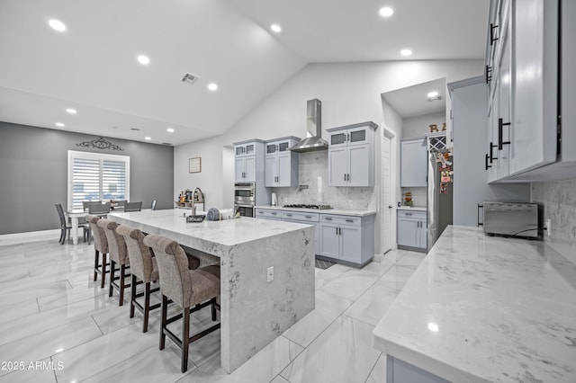 8017 S 143rd Ave, Goodyear, AZ 85338 - kitchen with wall chimney exhaust hood, appliances with stainless steel finishes, a breakfast bar area, a spacious island, and backsplash