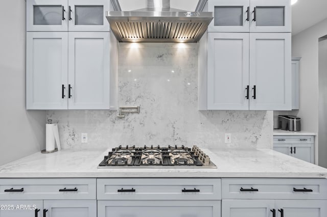 8017 S 143rd Ave, Goodyear, AZ 85338 - kitchen featuring wall chimney exhaust hood, stainless steel gas cooktop, backsplash, and glass insert cabinets