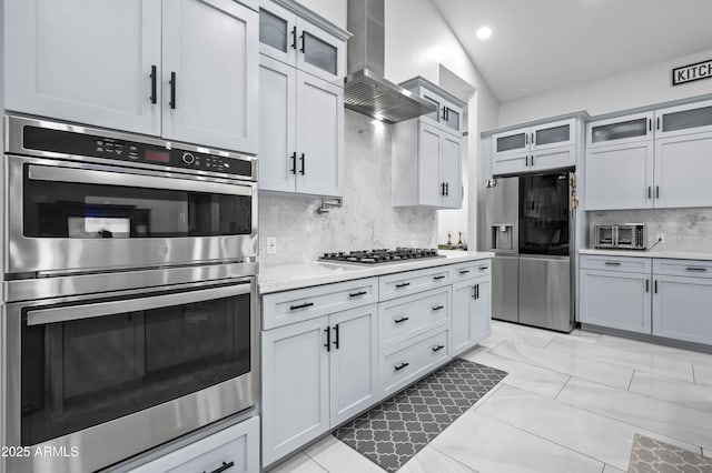 8017 S 143rd Ave, Goodyear, AZ 85338 - kitchen featuring appliances with stainless steel finishes, wall chimney range hood, decorative backsplash, glass insert cabinets, and recessed lighting
