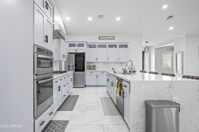 8017 S 143rd Ave, Goodyear, AZ 85338 - kitchen with a breakfast bar area, stainless steel appliances, recessed lighting, light marble finish floors, and glass insert cabinets