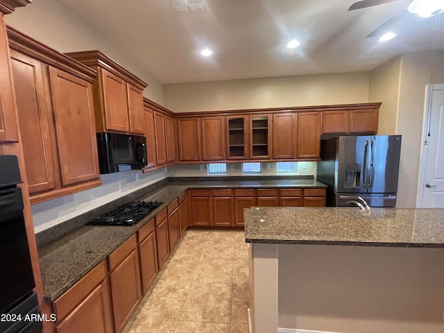 kitchen with dark stone countertops, ceiling fan, and black appliances