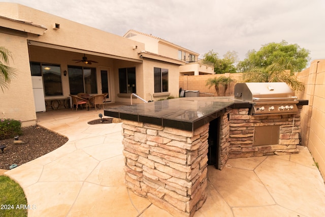 view of patio / terrace featuring a grill, ceiling fan, a bar, and exterior kitchen