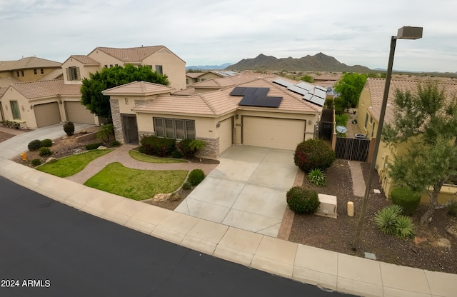 view of front of house with a mountain view, solar panels, and a garage