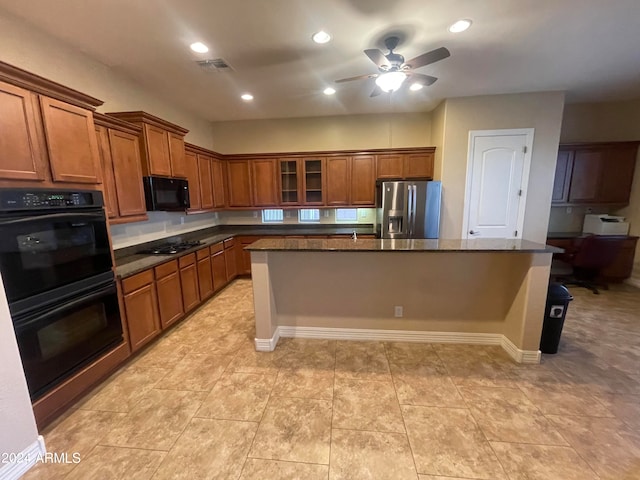 kitchen with ceiling fan, dark stone countertops, a kitchen bar, a kitchen island, and black appliances