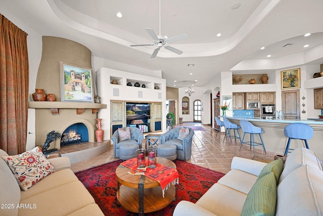 tiled living room featuring arched walkways, recessed lighting, a fireplace, and a raised ceiling