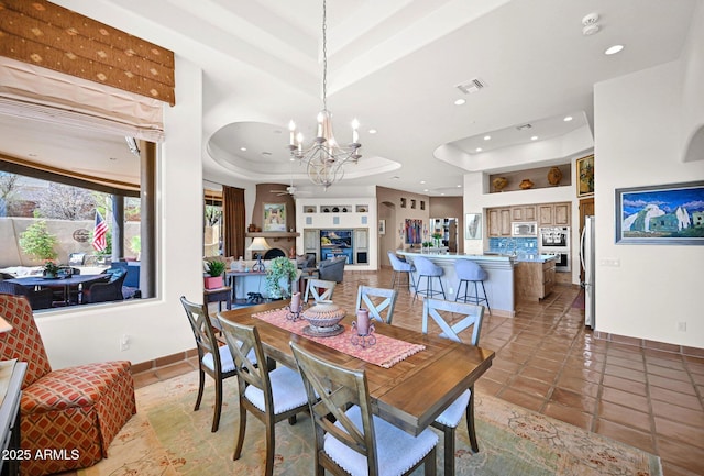 dining area with visible vents, a tray ceiling, recessed lighting, a fireplace, and a chandelier