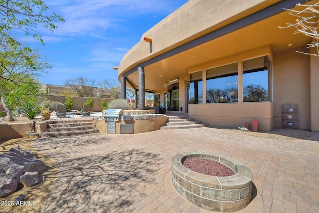 view of patio with area for grilling, an outdoor fire pit, and fence