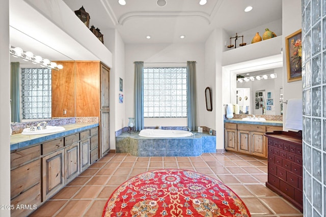 full bathroom featuring a sink, a garden tub, two vanities, and tile patterned flooring