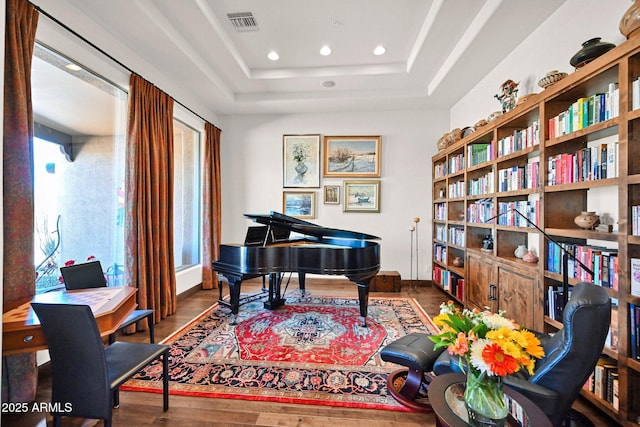 living area featuring visible vents, recessed lighting, a tray ceiling, and wood finished floors