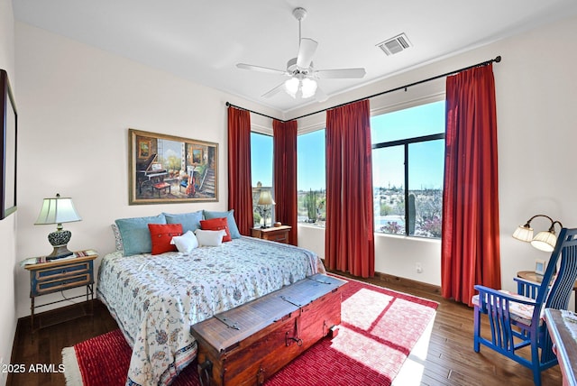 bedroom featuring ceiling fan, visible vents, baseboards, and wood finished floors