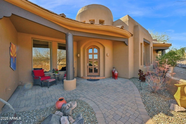 entrance to property with a patio area, stucco siding, and french doors