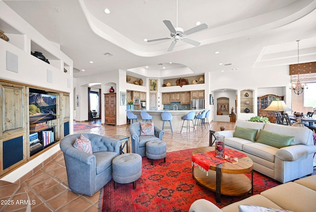 living room with light tile patterned floors, built in features, a tray ceiling, recessed lighting, and arched walkways