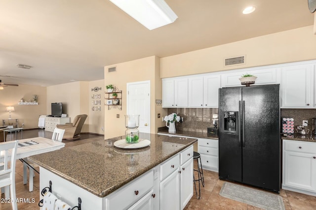 kitchen with black fridge with ice dispenser, visible vents, and backsplash