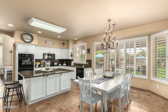 kitchen with arched walkways, white cabinets, black appliances, and tasteful backsplash