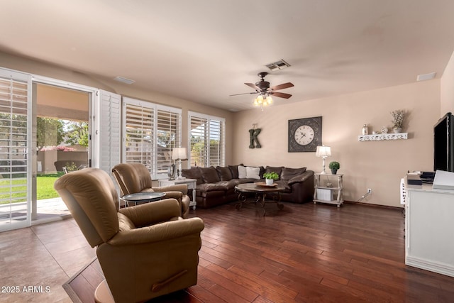 living room with hardwood / wood-style floors, baseboards, visible vents, and ceiling fan