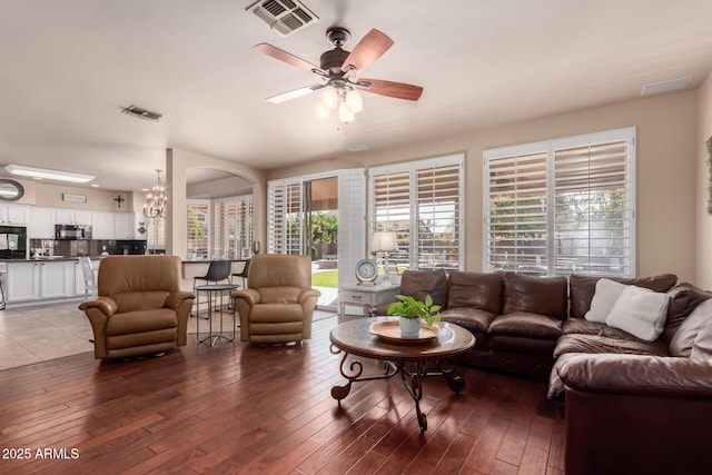 living area with visible vents, wood finished floors, and ceiling fan with notable chandelier