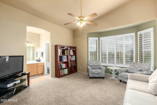 living area featuring light carpet, arched walkways, a ceiling fan, and lofted ceiling