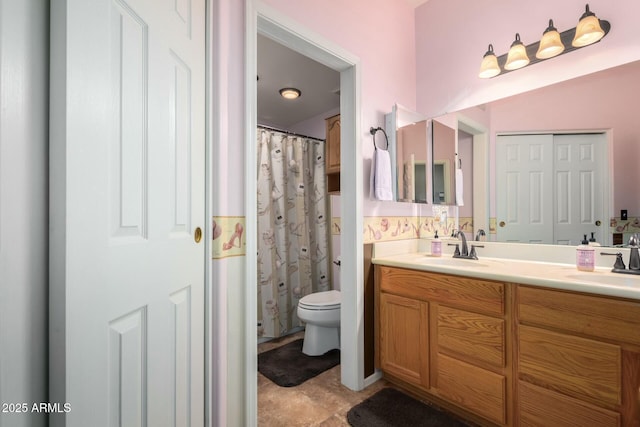 full bathroom with double vanity, toilet, and a sink